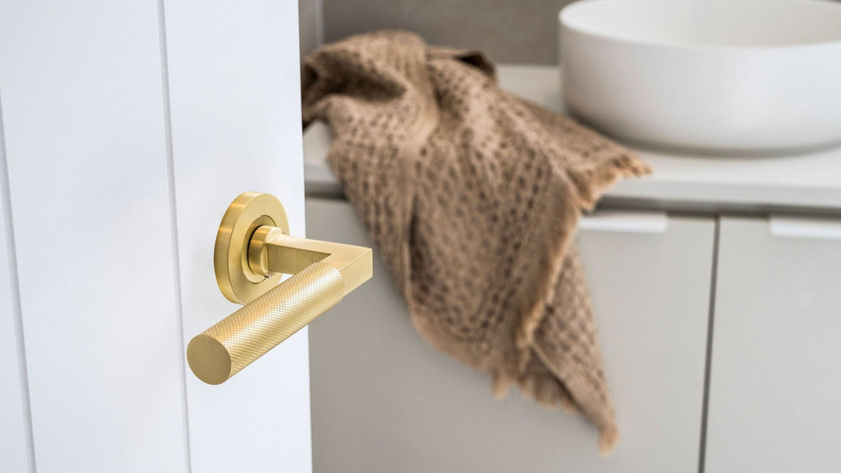Brushed brass door handle installed on a bathroom door